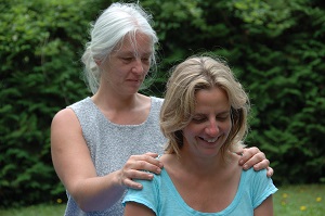 Eine TherapeutIn berührt eine zweite Person an den Schultern